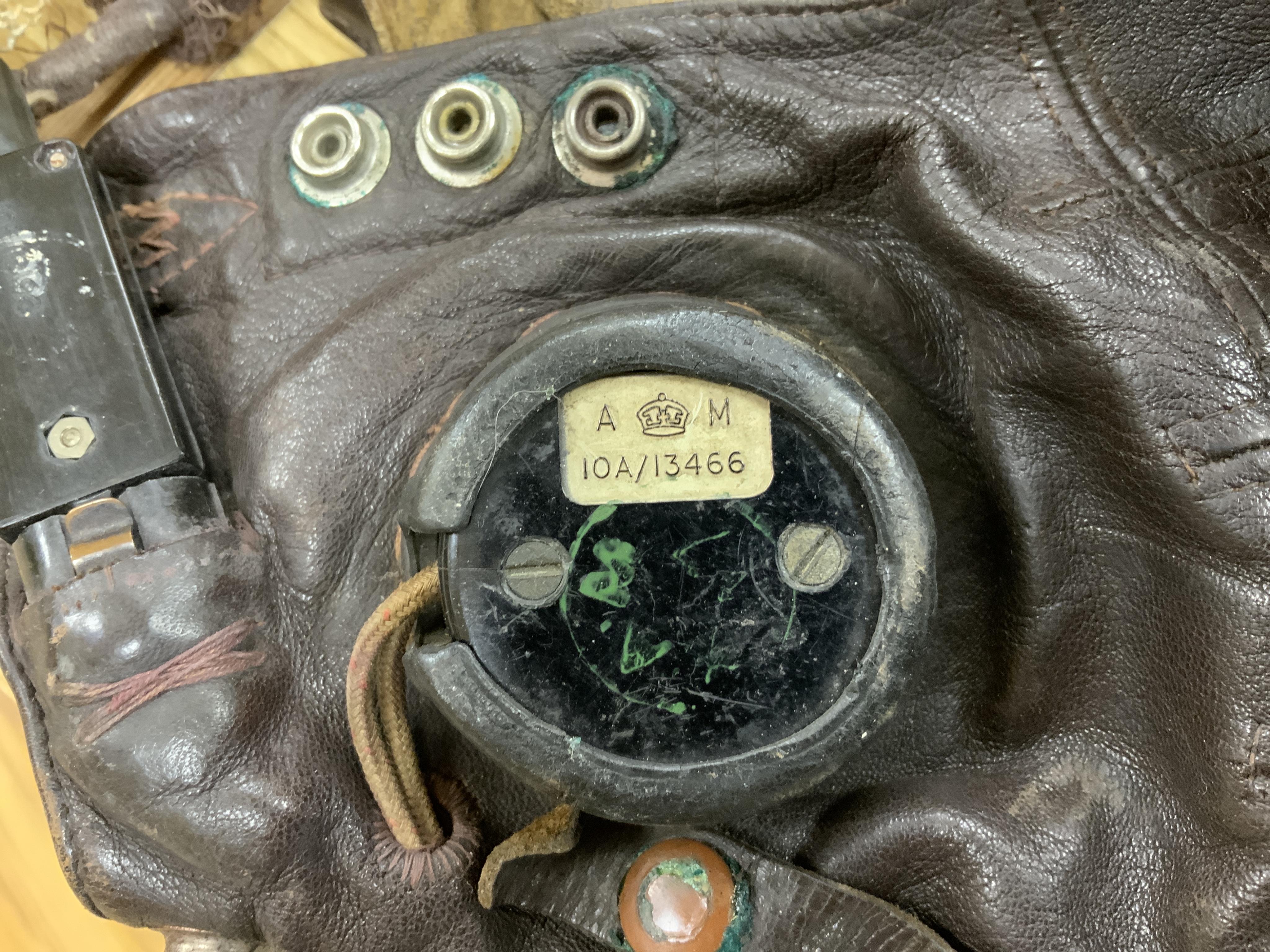 A WWII RAF Air Ministry aviator’s leather head-gear, with built-in padded headphones, oxygen mask with microphone and other electrics incorporated into it, marked with a crown and ‘AM 10A/13466’ to one earpiece, together